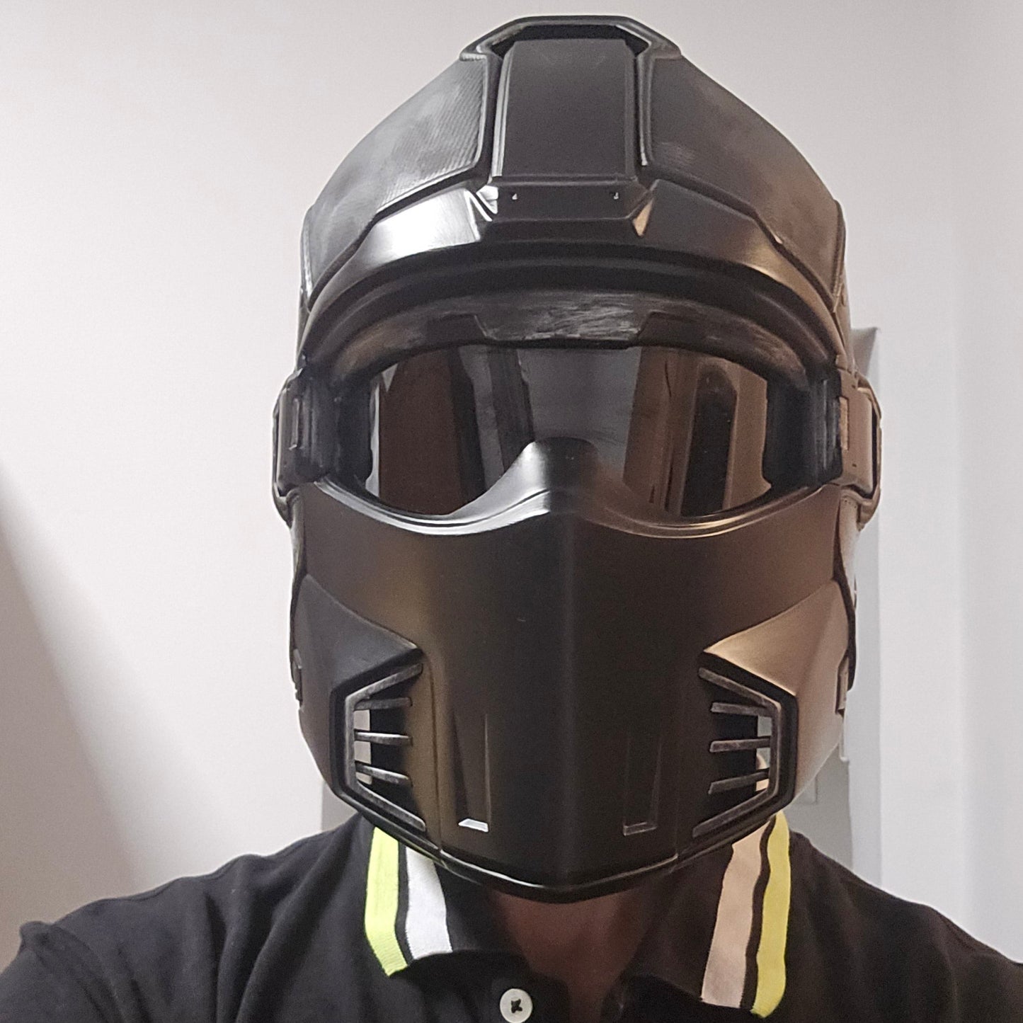 A black full-face motorcycle helmet with a dark tinted visor, shown being worn by a person in a black Champion polo shirt.